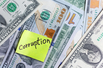 Yellow stick note on an USD money background. The inscription 