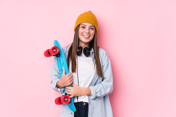 Young skater woman holding a skate happy, smiling and cheerful.
