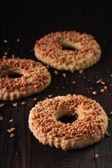 Crunchy shortbread rings with peanut sprinkle on wooden background