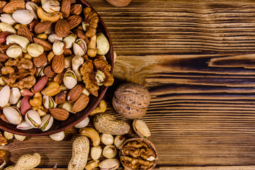 Various nuts (almond, cashew, hazelnut, pistachio, walnut) in ceramic plate on a wooden table. Vegetarian meal. Healthy eating concept. Top view
