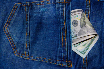 American banknotes in jeans pocket. A note in denominations of $ 100 peeps, stick out from the back, the foremost pants pocket. Money falls out of pocket. Flare effect. View from different angles