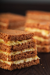 Sliced russian honey cake with cream cheese on rustic wooden background