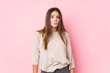 Young caucasian woman posing isolated shrugs shoulders and open eyes confused.
