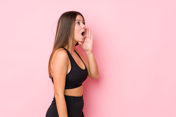 Young fitness caucasian woman isolated shouting and holding palm near opened mouth.