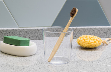 Bamboo eco toothbrushes with multicolored bright bristles in a glass in bathroom