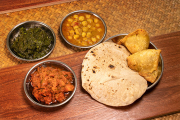 Indian various food with spice curry and naan bread and samosa on wooden table in restaurant.