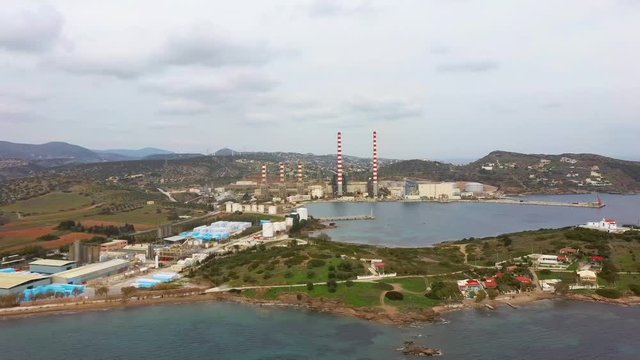 Aerial view of sea bay with old factory and a small white church, low vegetation mountains, Lavrio Greeceside, side movement by drone