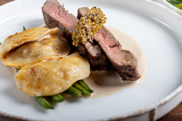 Grilled meat steak New York Striploin. Dumplings with porcini mushrooms in asparagus truffle sauce. On a wooden board on a dark background.