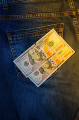 American banknotes in jeans pocket. A note in denominations of $ 100 peeps, stick out from the back, the foremost pants pocket. Money falls out of pocket. Flare effect. View from different angles