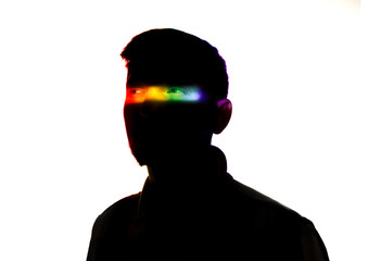 Attented. Dramatic portrait of a man in the dark on white studio background with rainbow colored line. Hidden things, human rights, equality, LGBT people's pride concept. Art elegance, creative.