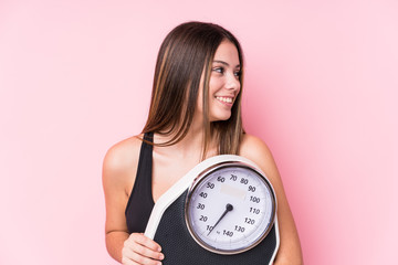 Young caucasian sporty woman holding a scale