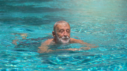 Senior man swimming in  swimming pool