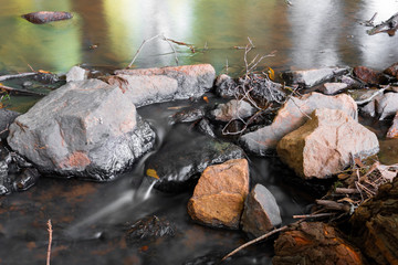 Long exposure picture of a stream flowing with rocks and natural light