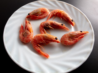 Red shrimp in a white plate on a black