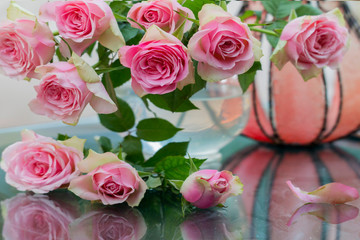 Glasvase mit rosa Rosen als Tischdekoration im Garten