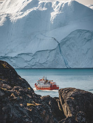 Orange whale Watching tour boat ship with icebergs in background. View towards Icefjord in Ilulissat. Greenland Disko Bay. Icebergs reflecting sunlight on a summer day. © Mathias