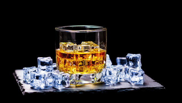 Whiskey on the rocks, whiskey glass, ice cubes on a slate board
