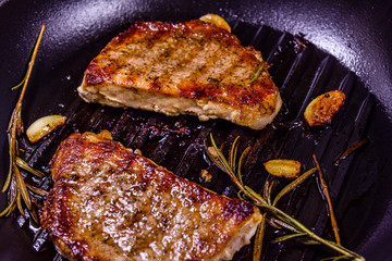 Roasted steaks with garlic, rosemary and spices in a cast iron grill pan