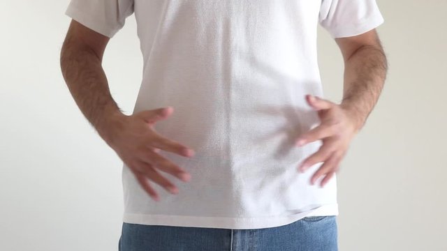 自分のお腹を軽くたたくシャツを着た男性