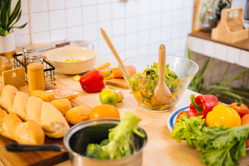 Preparing for cooking salad, vegetable in the big bowl and bread on wooden cut board in the kitchen at home