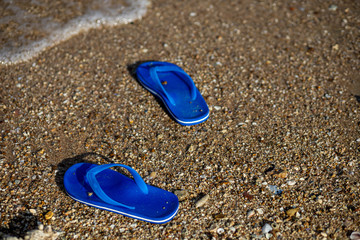 Fototapeta na wymiar Pair of flip flops on the beach and water flow.