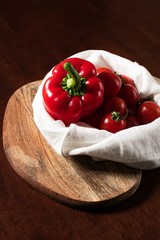 Tomatoes and peppers in a linen bag on a dark background
