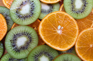 Kiwi and orange sliced circles lie on a flat surface texture