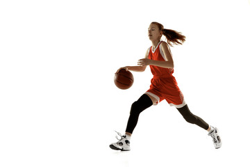 Young caucasian female basketball player in action, motion in run isolated on white background. Redhair sportive girl. Concept of sport, movement, energy and dynamic, healthy lifestyle. Training.