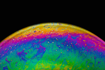 Rainbow soap bubble on an isolated black background. Close-up of the colorful surface. Poster blank