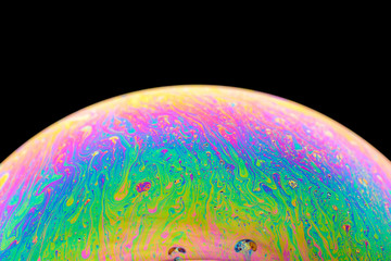 Rainbow soap bubble on an isolated black background. Close-up of the colorful surface. Poster blank © spritnyuk