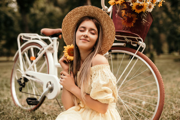 Pleased woman with sunflower sitting near retro bike