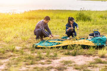 People Pitch a tent on the ground near the lake at sunset. Relaxing, traveling, long weeked, holiday concept.