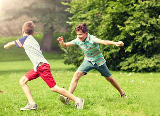friendship, childhood, leisure and people concept - group of happy kids or friends playing catch-up game and running in summer park