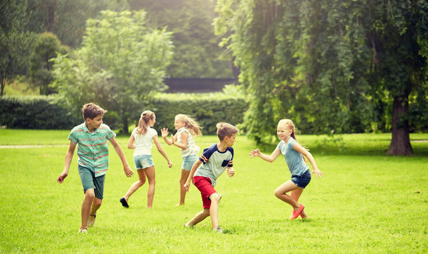 friendship, childhood, leisure and people concept - group of happy kids or friends playing catch-up game and running in summer park