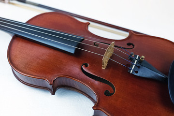 The wooden violin put on white background,in front of blurred bow,show front side of string instrument