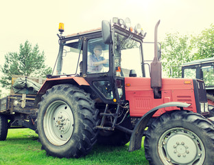 farming, agriculture and people concept - senior man driving tractor at farm