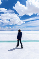 Back view of a young woman walkig on a salt flat in Salta, Argentina