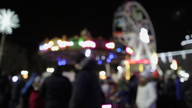 Defocused outdoor holiday fair in winter city shining wih colorful lights at night.