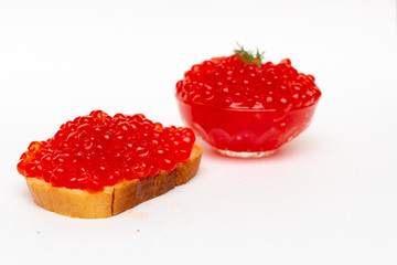 Red caviar on white bread and in a transparent cup on a white background