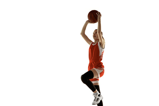 Young caucasian female basketball player in action, motion in jump isolated on white background. Redhair sportive girl. Concept of sport, movement, energy and dynamic, healthy lifestyle. Training.