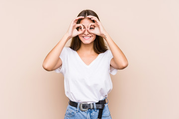 Young caucasian woman posing isolated showing okay sign over eyes