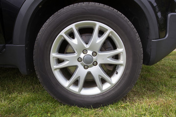 Obraz premium Modern unidentifiable black suv car wheel on rural roadside, closeup frontal photo