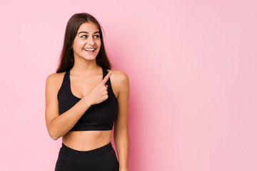 Young caucasian fitness woman doing sport isolated smiling and pointing aside, showing something at blank space.