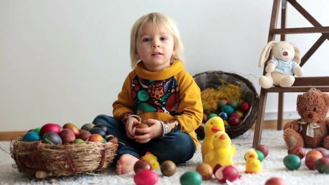 Toddler child, blonde boy playing with Easter eggs. Children plays with eggs and chicks