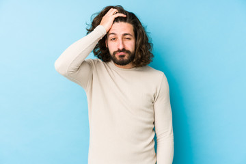 Young long hair man isolated on a blue background tired and very sleepy keeping hand on head.