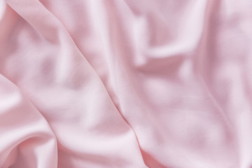 Pink wrinkled silk fabric. The pink fabric is laid out waves. Pink fabric background or texture.