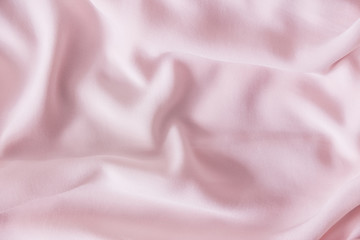Pink wrinkled silk fabric. The pink fabric is laid out waves. Pink fabric background or texture.