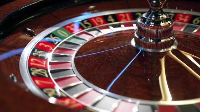 Casino: Roulette in Las Vegas with a white ball. The dealer croupier stops the roulette wheel and throws a game ball. The ball falls on the red field 1 one. Close-up