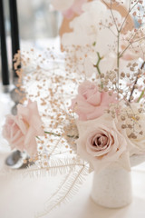Decorated dinner table with a vase of roses, gypsophila and calla lilies in white and pink. Floral composition from a fresh bouquet for a wedding event.