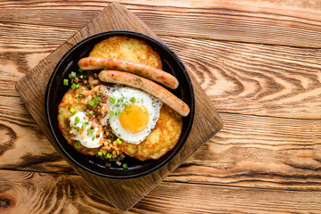 pan with fried egg, sausage and potato pancakes